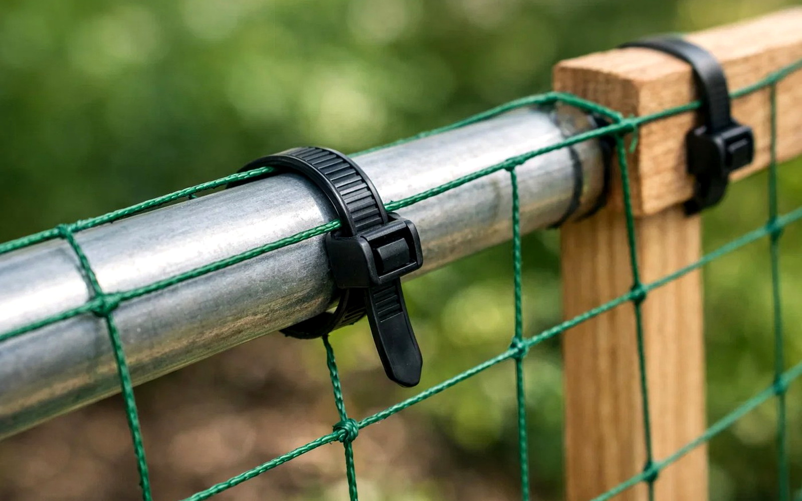 Agricultural netting fixed to pipe and wooden post with black cable ties