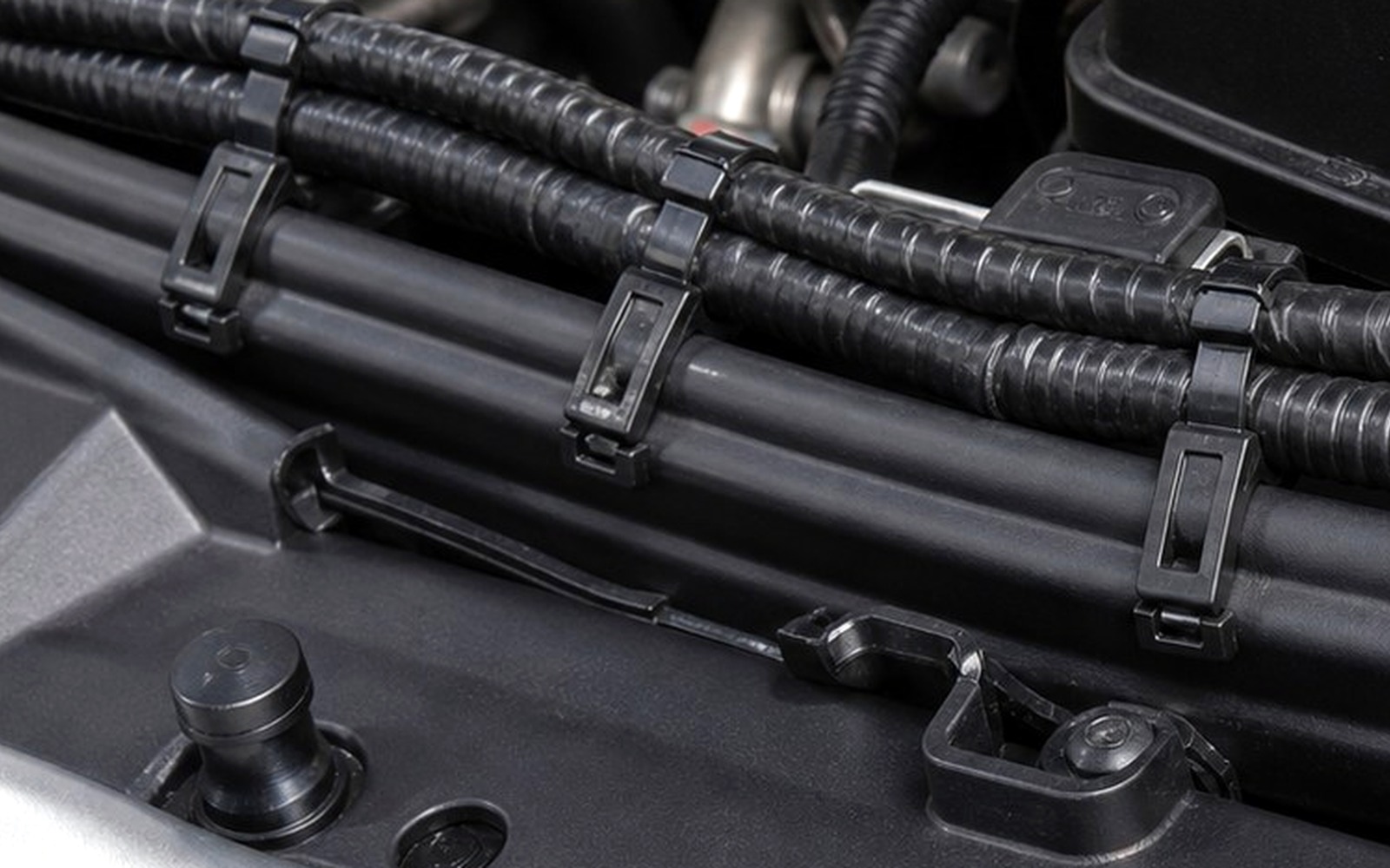 Close-up of automotive loom held with black cable ties in an engine bay