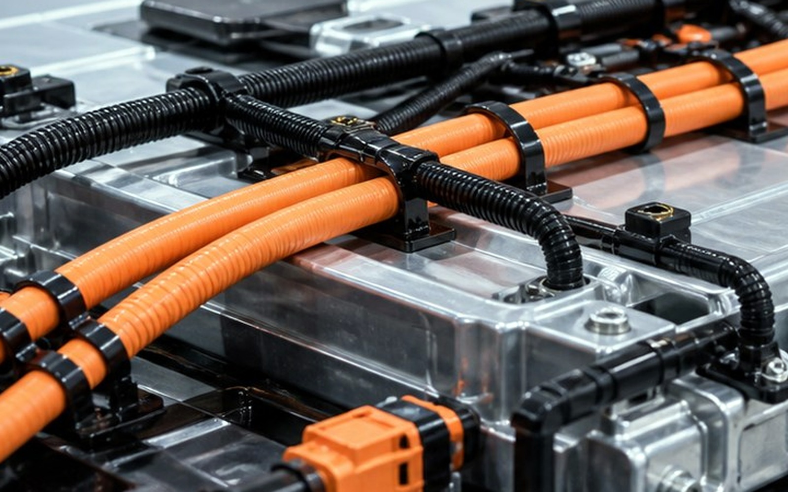 Close-up of EV orange high-voltage cables fixed along battery pack routing