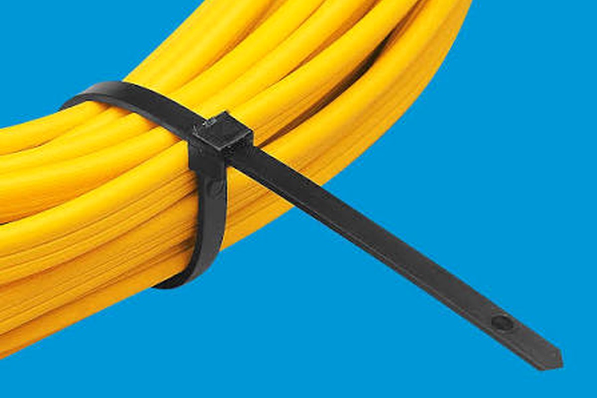 Cable tie fully wrapped around a yellow cable and pipe-style bundle