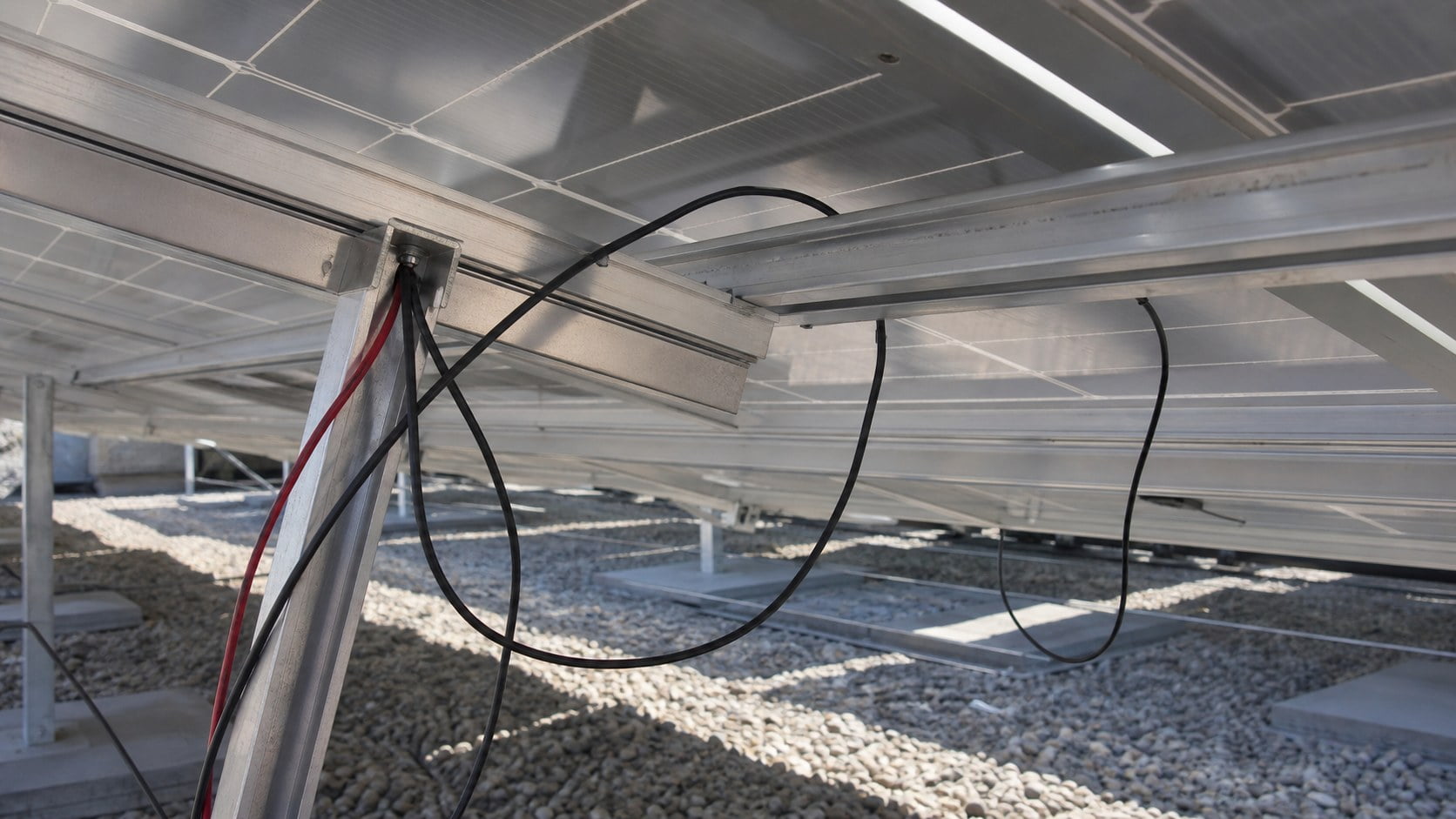 Loose PV cables hanging below solar module rail before cable management fixing